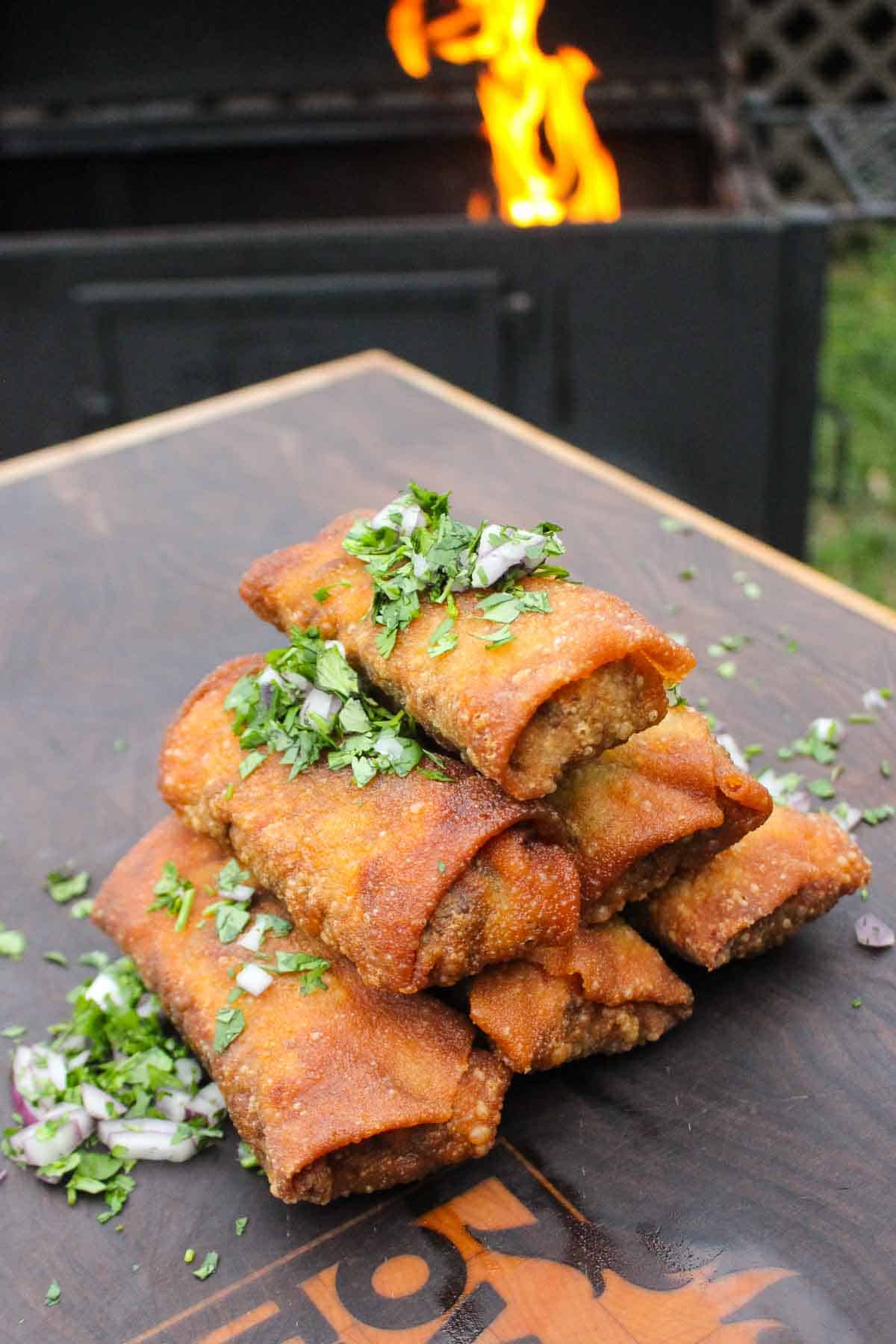 The egg rolls are stacked and sprinkled with cilantro and red onion. 