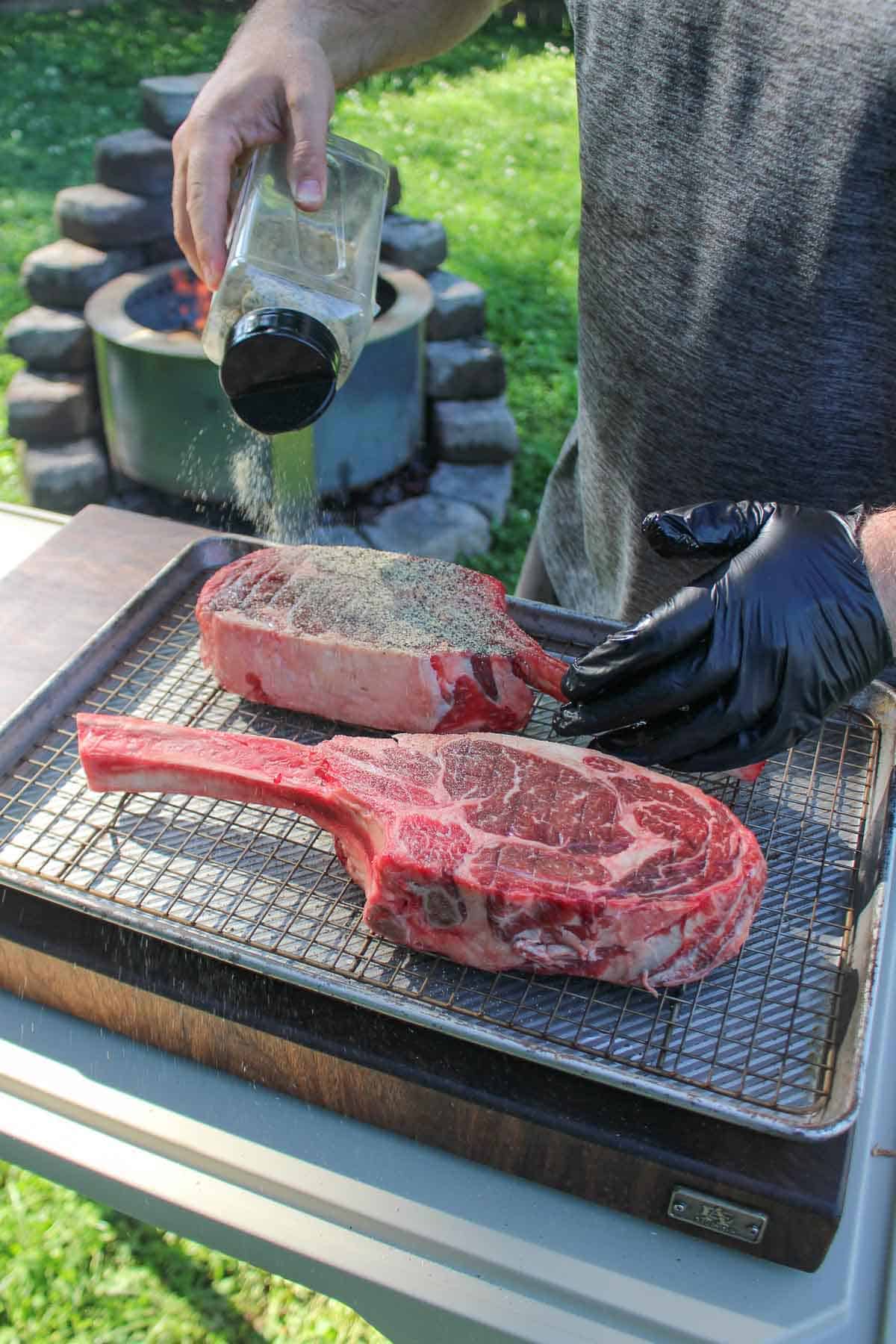 Seasoning the tomahawk steak for grilling.