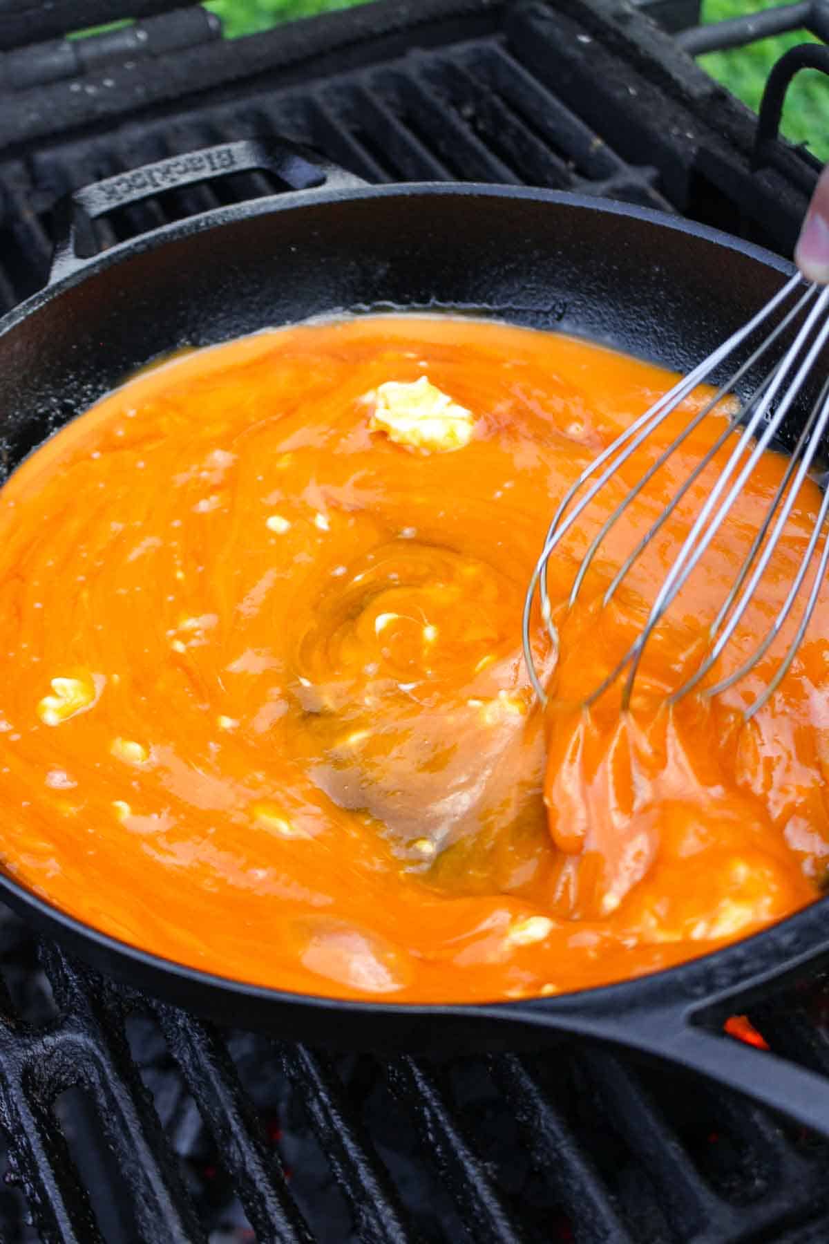 Buffalo sauce being mixed together on the grill.