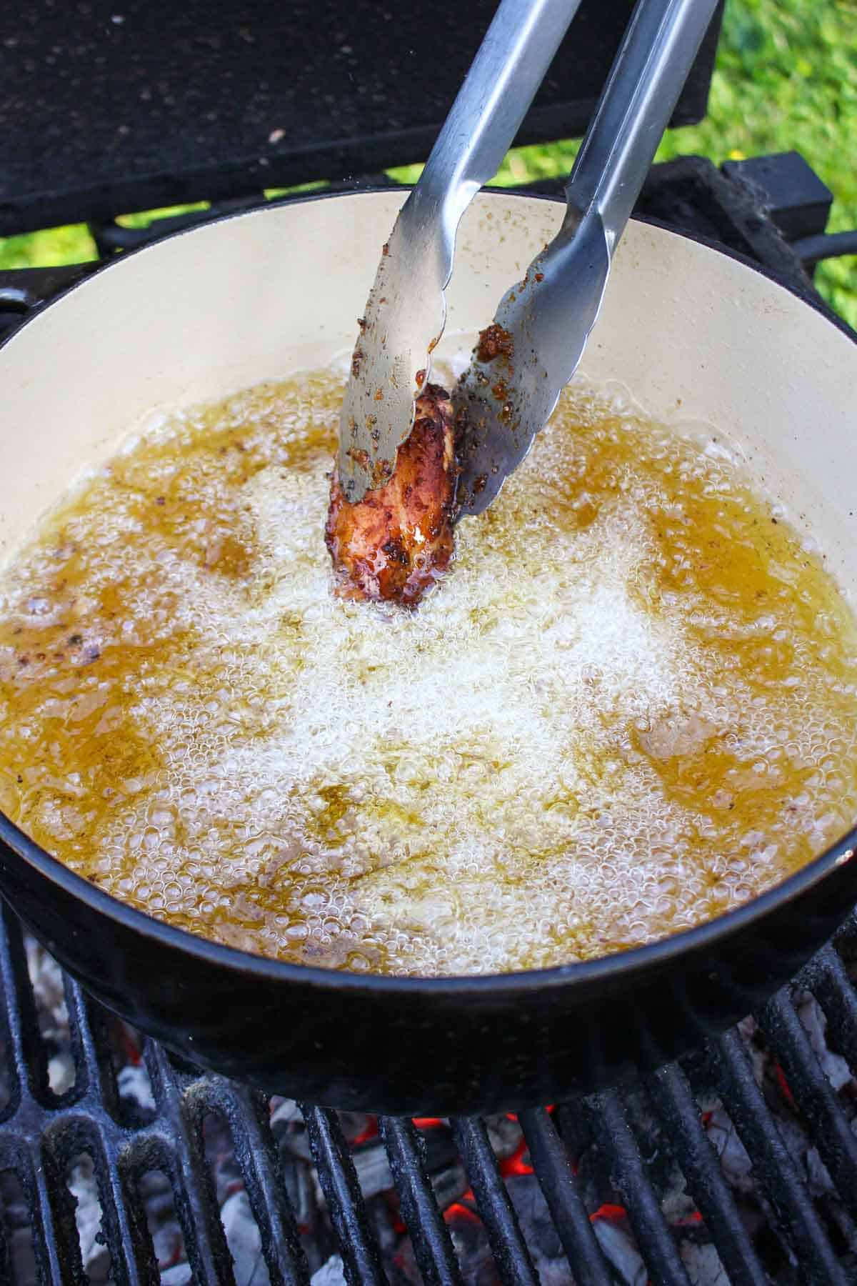 Dropping chicken into the frying oil for its second fry.