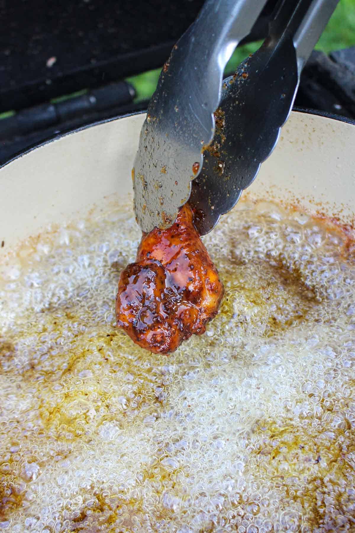 Frying the sauced Buffalo wings in oil.