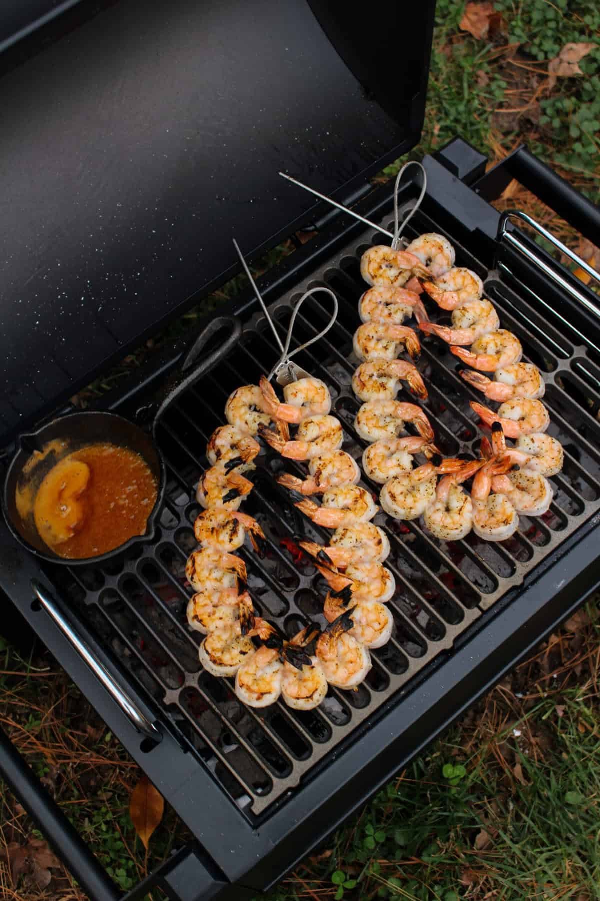 Shrimp strung on metal skewers and layer on the grill grate over hot coals. 
