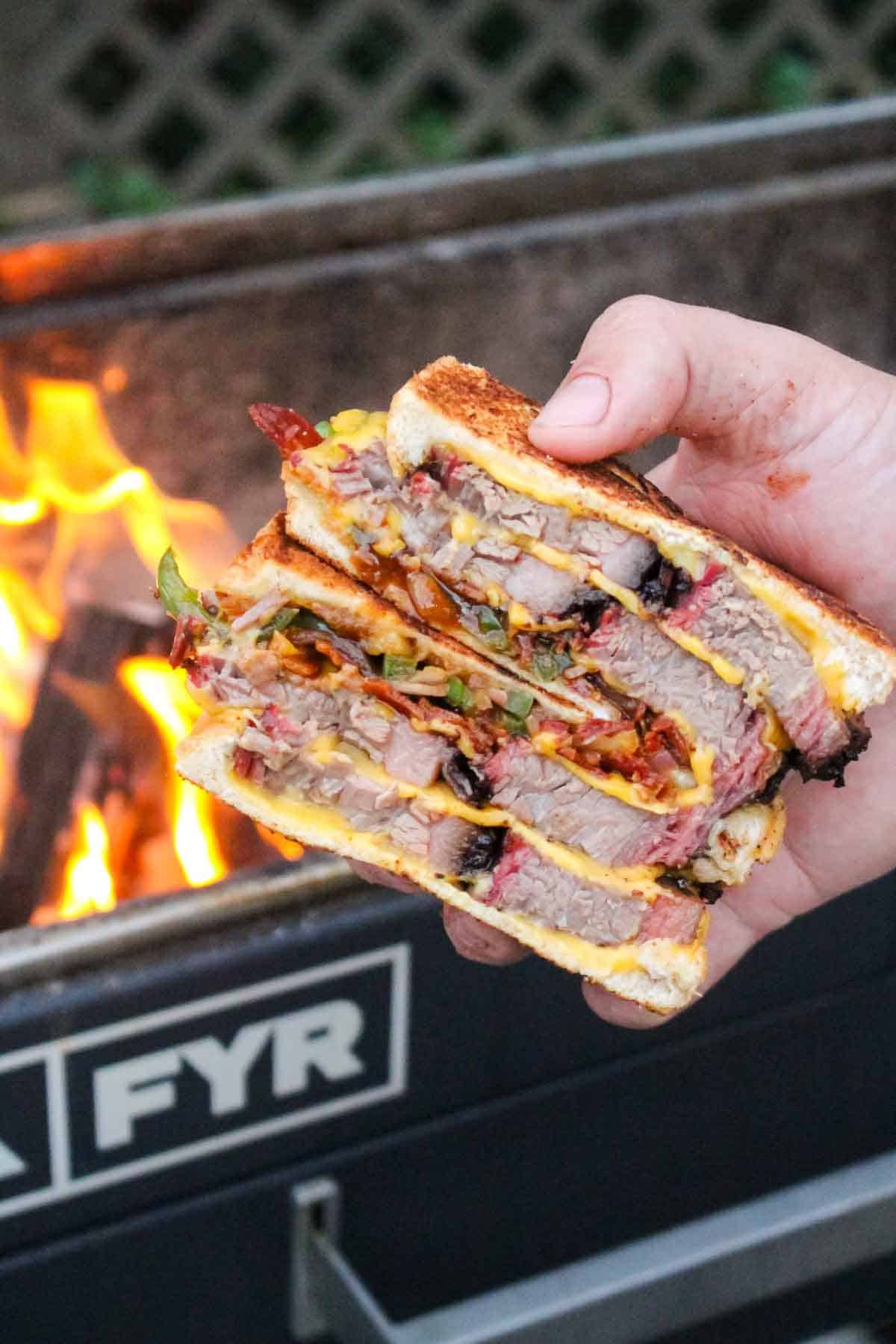 The BBQ brisket melt sliced in half and held up to the camera.