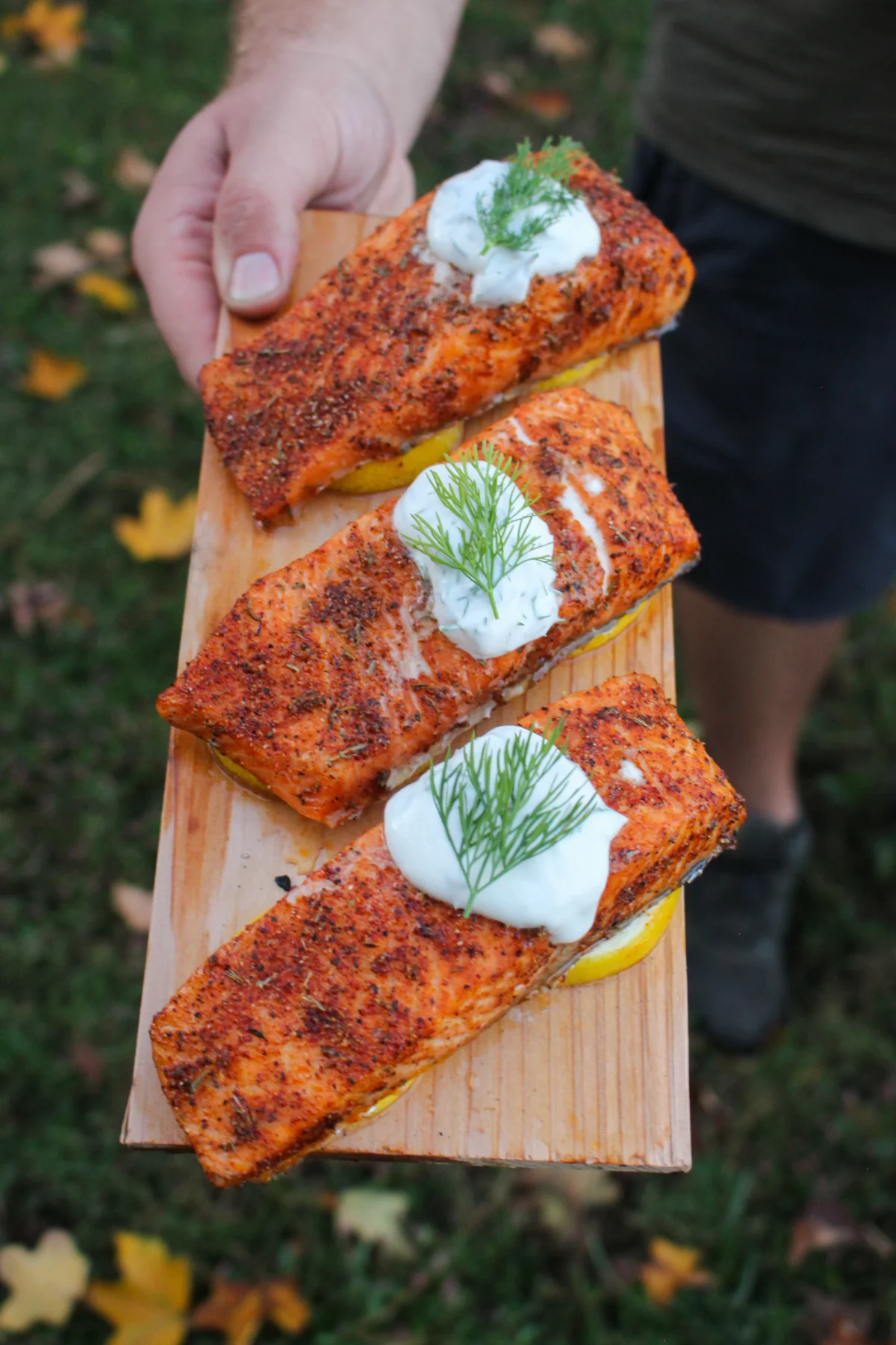 Three baked salmon filets on a wood plank