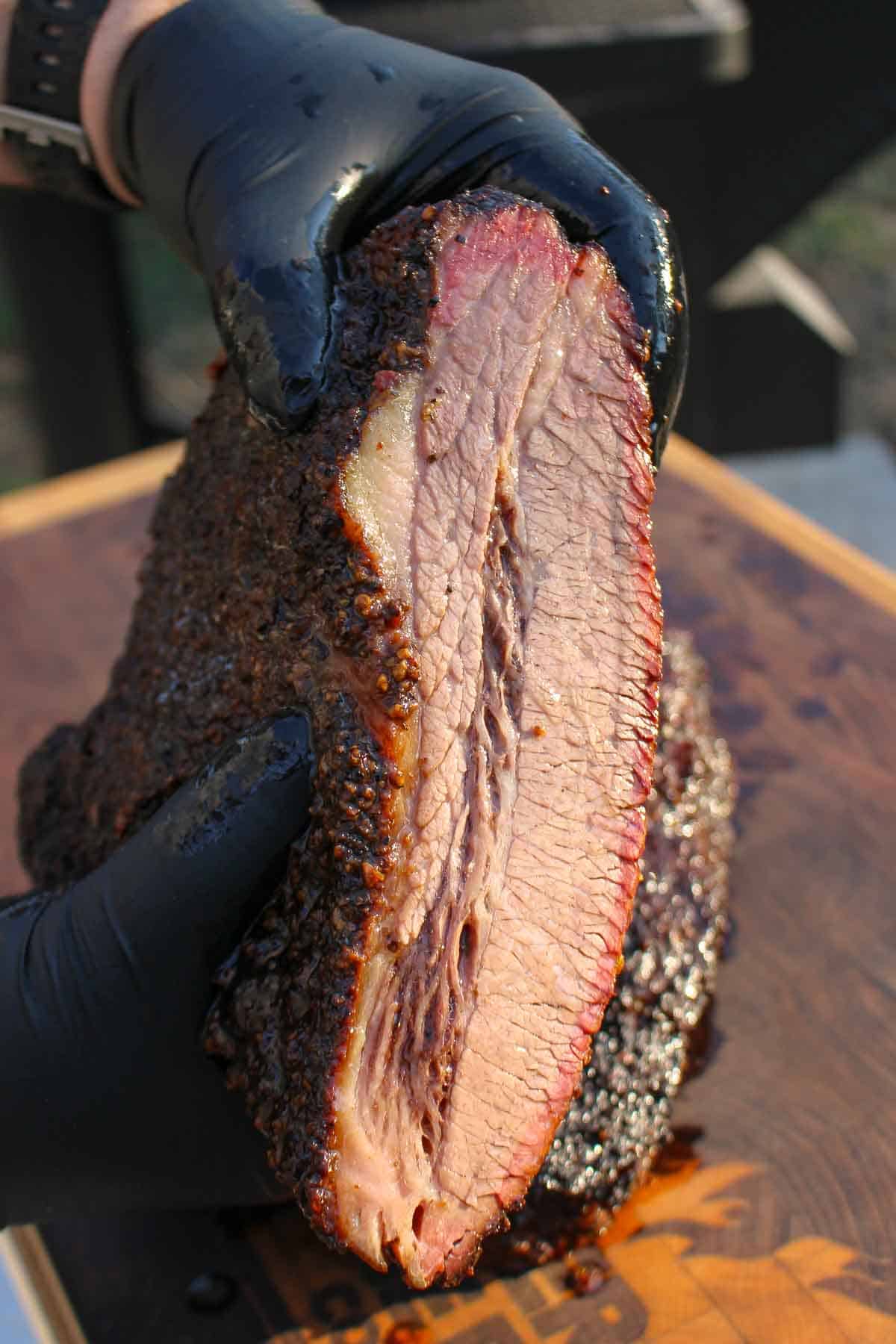 Holding up a sliced brisket so you can see the juices and texture. 