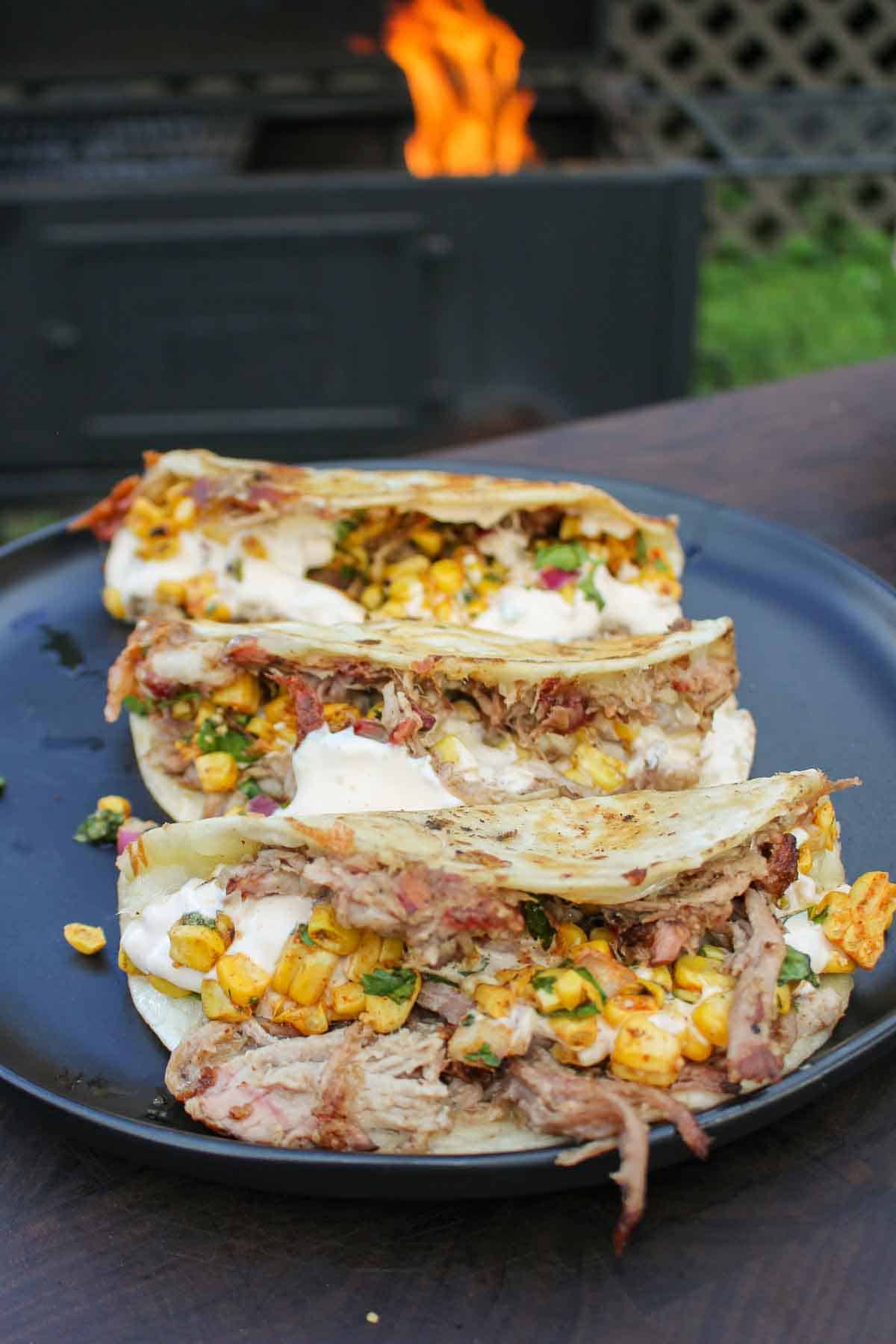 Pulled pork elote tacos sitting on a serving plate.