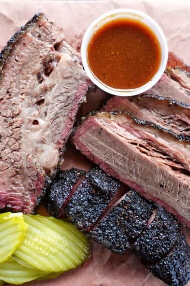 beef brisket is served with pickles and bbq sauce