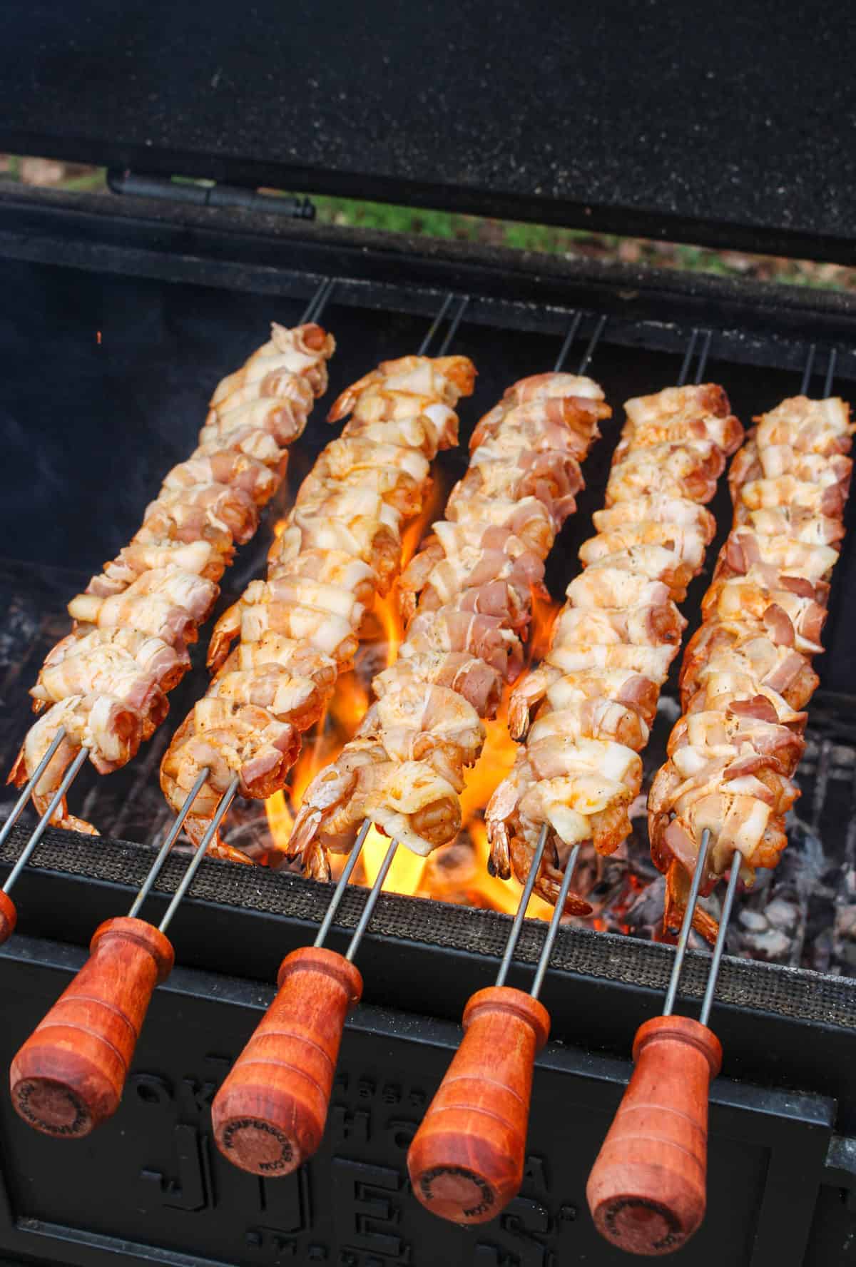 Bacon wrapped shrimp skewers getting started over the flames. 