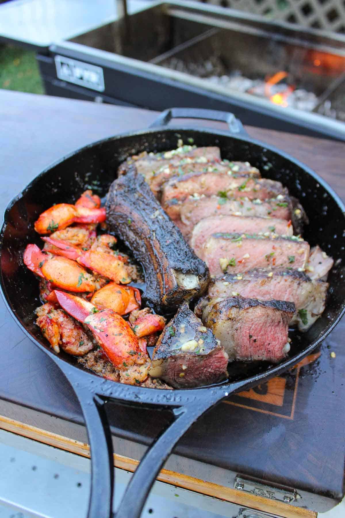 The sliced ribeye is served with some lobster meat all in a cast iron pan.