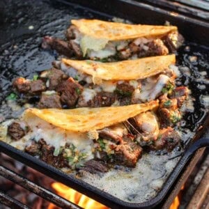 Three finished steak bite tacos on the grill.