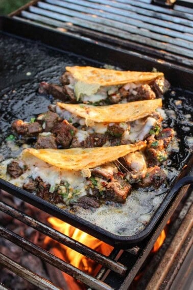 Three finished steak bite tacos on the grill.