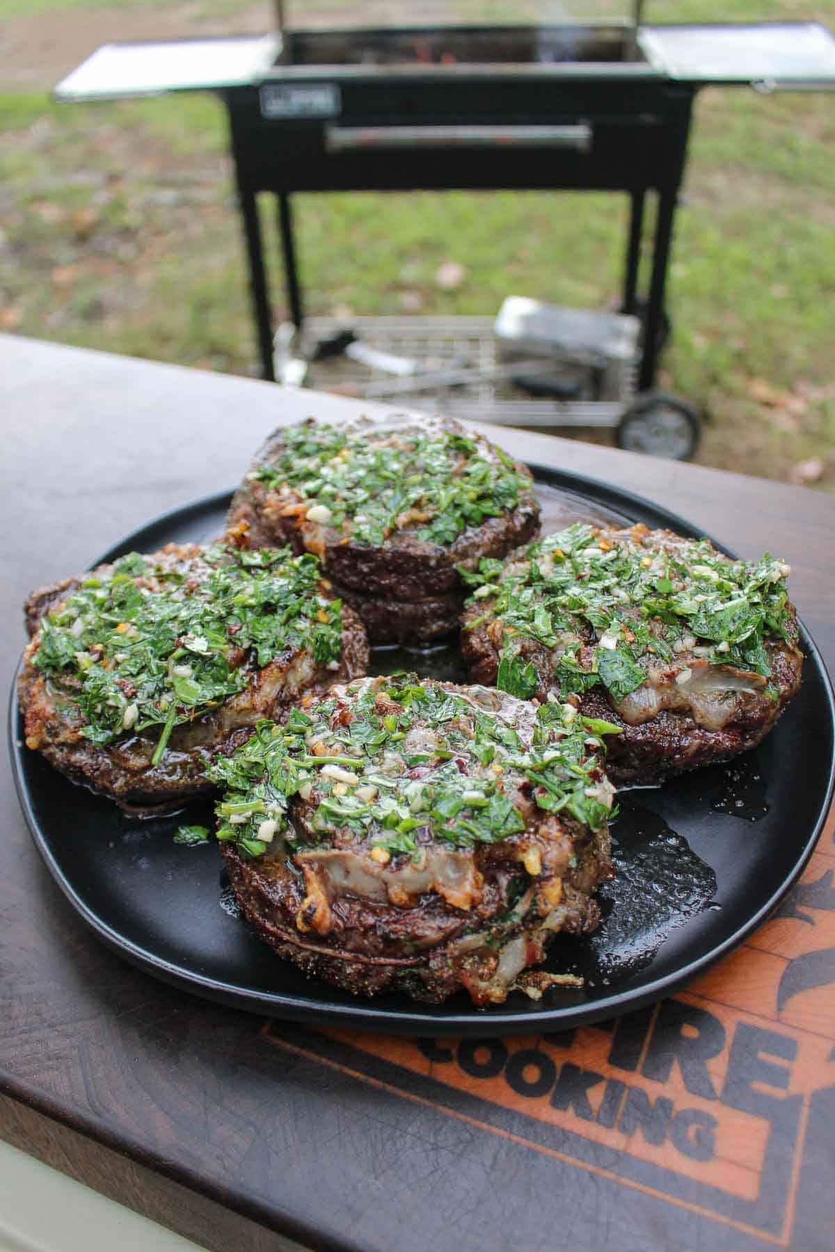 The grilled steaks have reached an internal temperature of 125 degrees F and are smothered in chimichurri for the final touch.