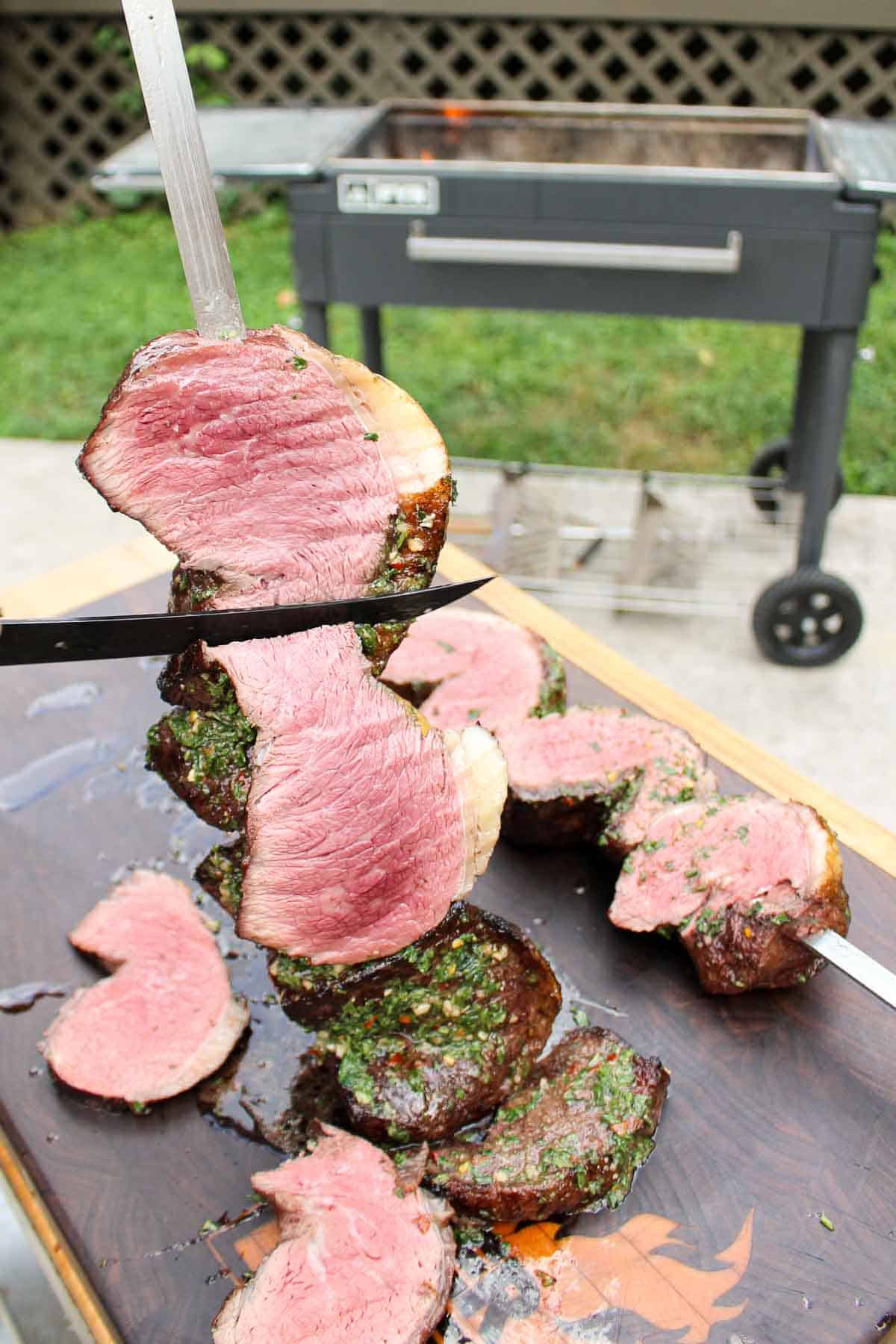 Slicing a piece of cooked picanha off the skewer.