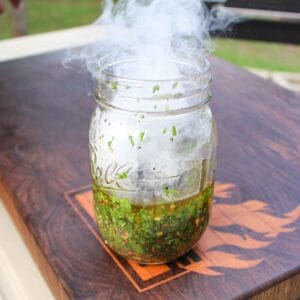 Smoke rising out of mason jar after adding charcoal to the chimichurri.