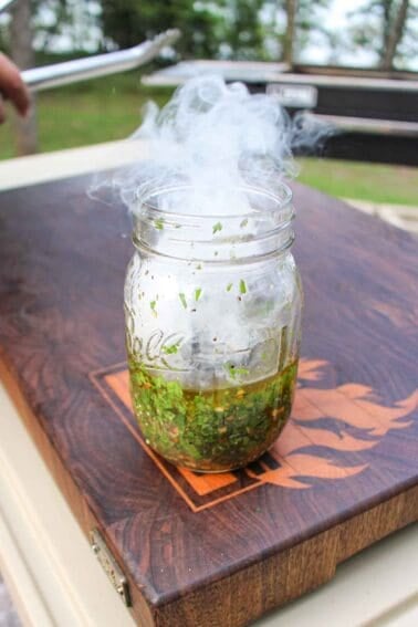 Smoke rising out of mason jar after adding charcoal to the chimichurri.