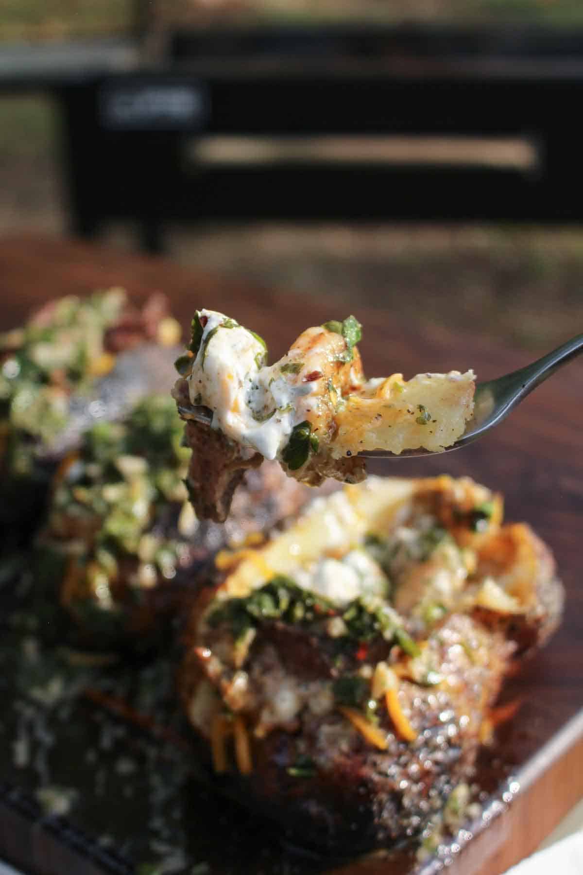 A forkful of surf and turf baked potato with shrimp and steak