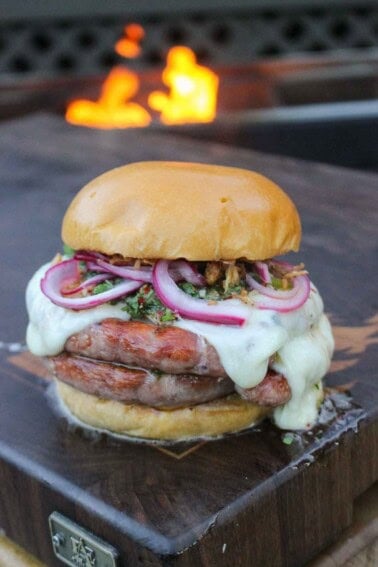 The Choripan Burger is a work of art that combines all the best flavors of sausage, cheese, and pickled onions.