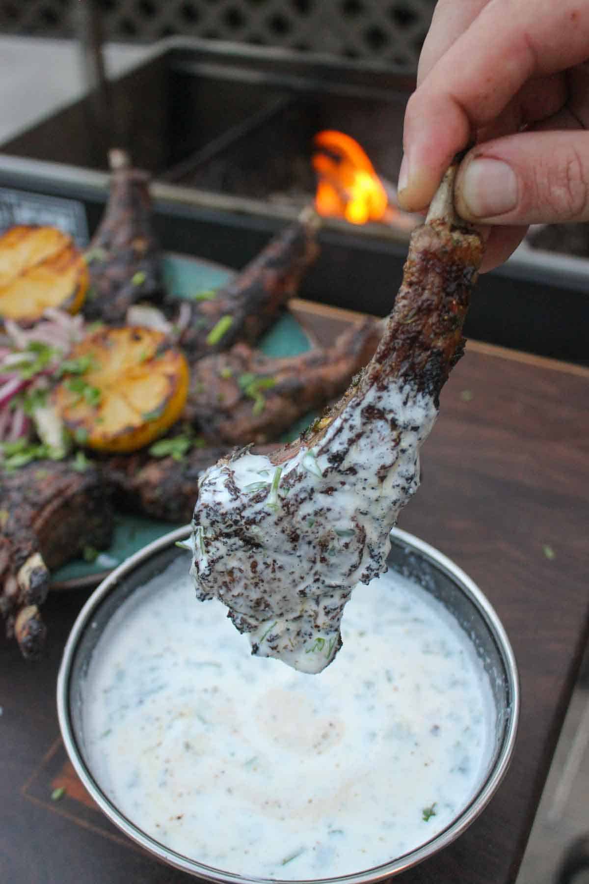 Diving into the minty yogurt sauce with a grilled and tasty lamb chop ready to go!