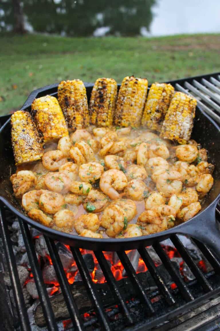 The grilled corn is cut in half and placed in the cast iron pan with all the flavorful and buttery shrimp.