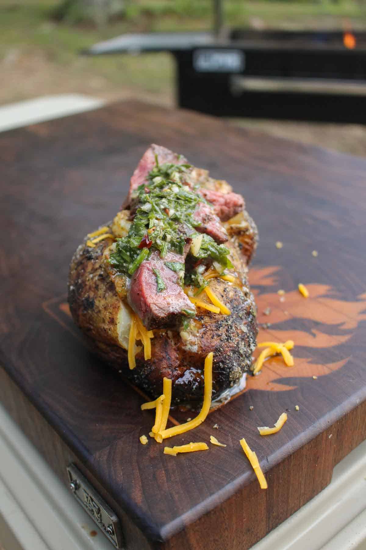 A surf and turf baked potato, with a Russet potato as the base and steak, shrimp, shredded cheese and chimichurri butter as toppings