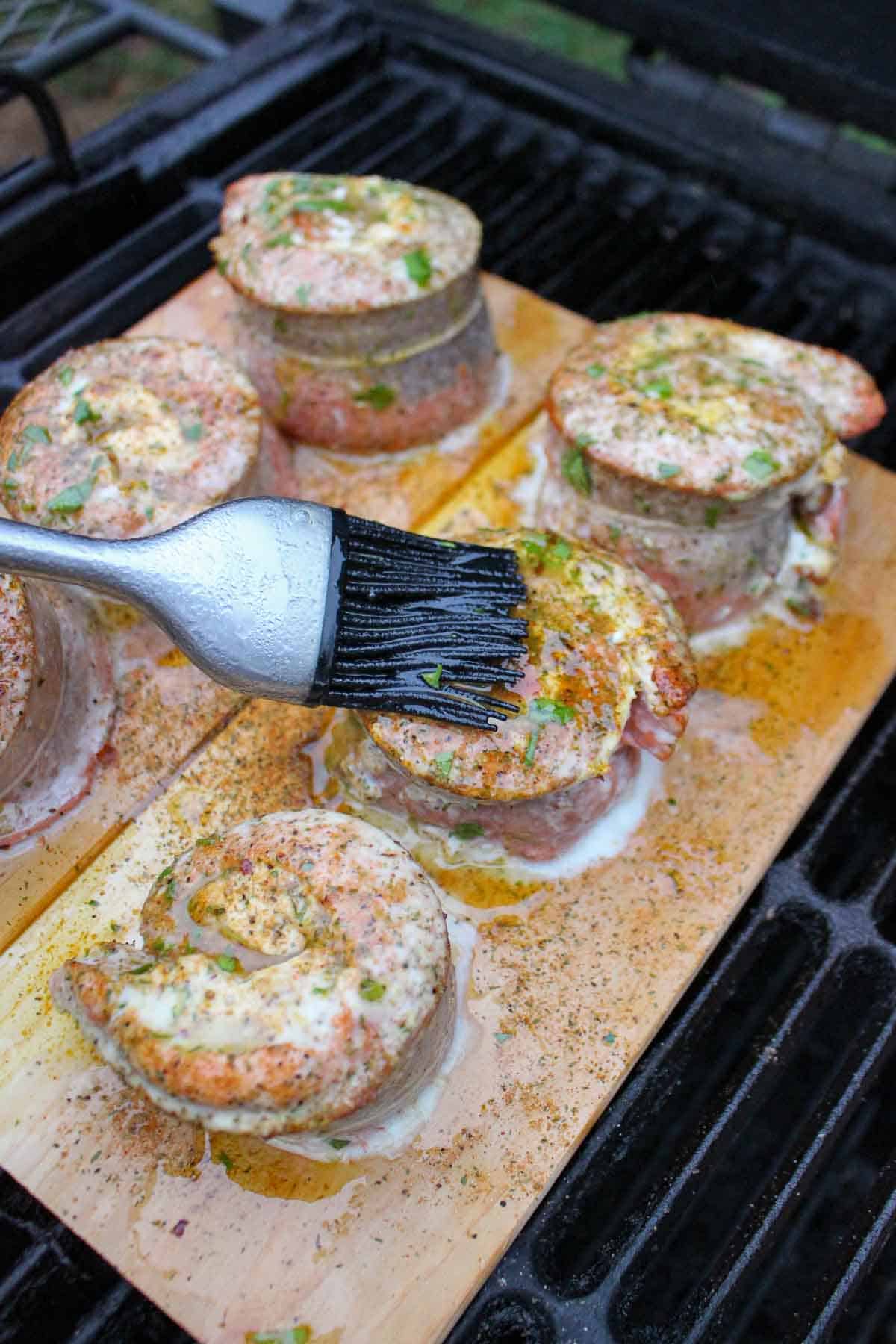 A brush basting smoked salmon pinwheels with butter and FYR Gold glaze