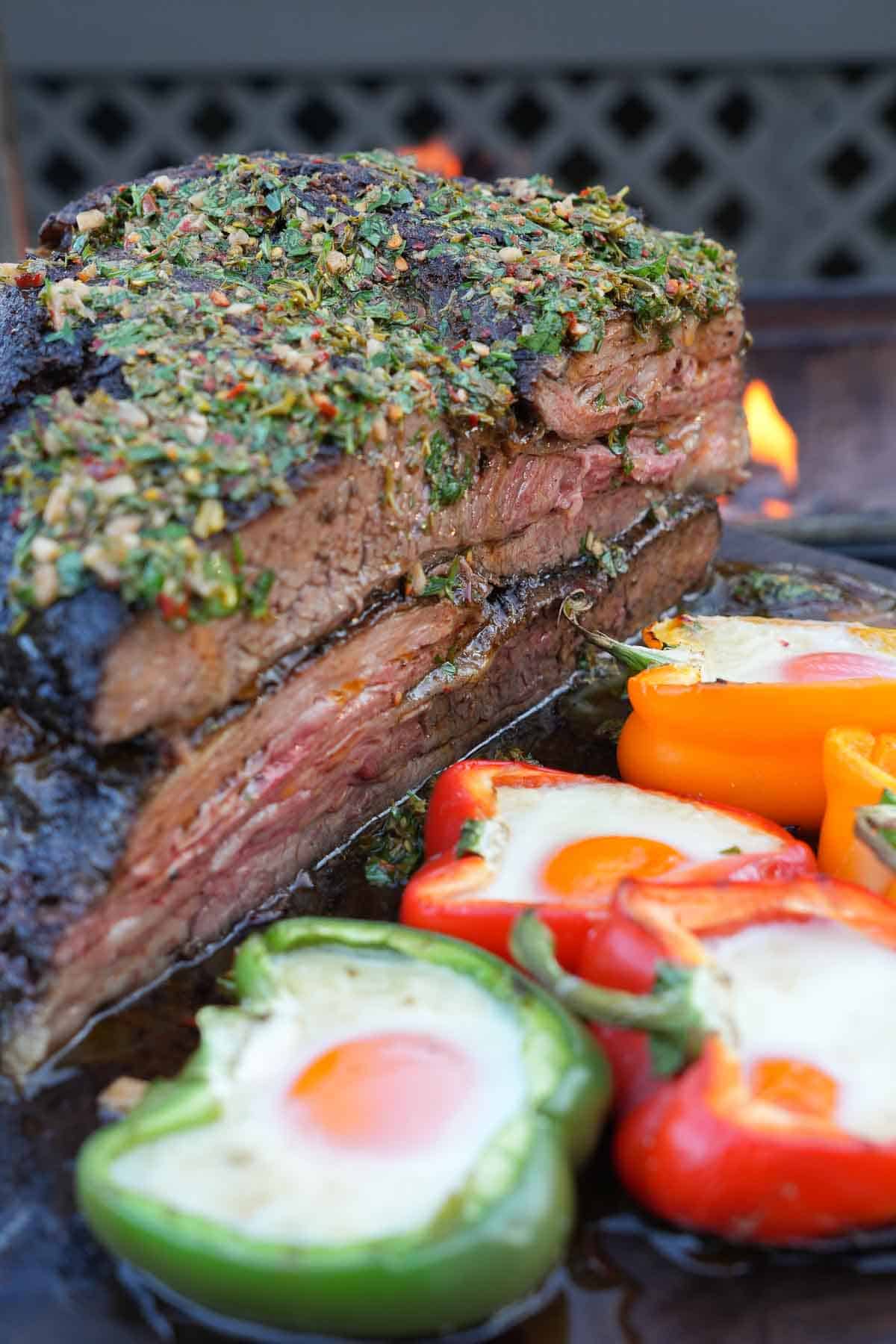 The Grilled Vacio is a massive cut of beef that is not normal to find in the United States. Here it's cooked and sliced in half and served up beside the bell peppers filled with egg and cheese.