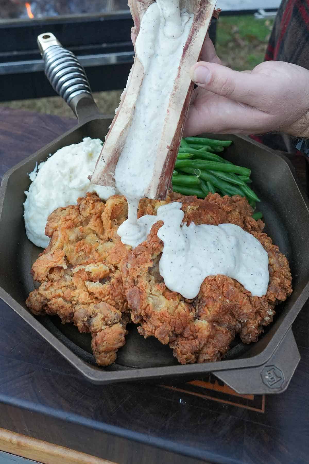 Our Chicken Fried Steak is smothered in the Bone Marrow Gravy that we make in our Finex Cast Iron pan.