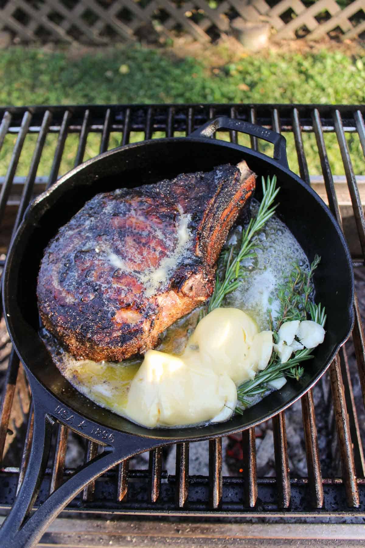 Ribeye in a cast iron pan ready to get basted with it's basting ingredients