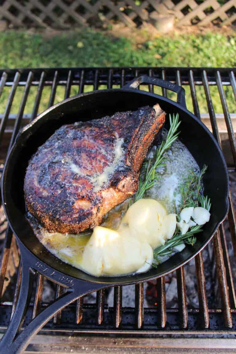 Ribeye Steak in a cast iron skillet along with all basting ingredients.