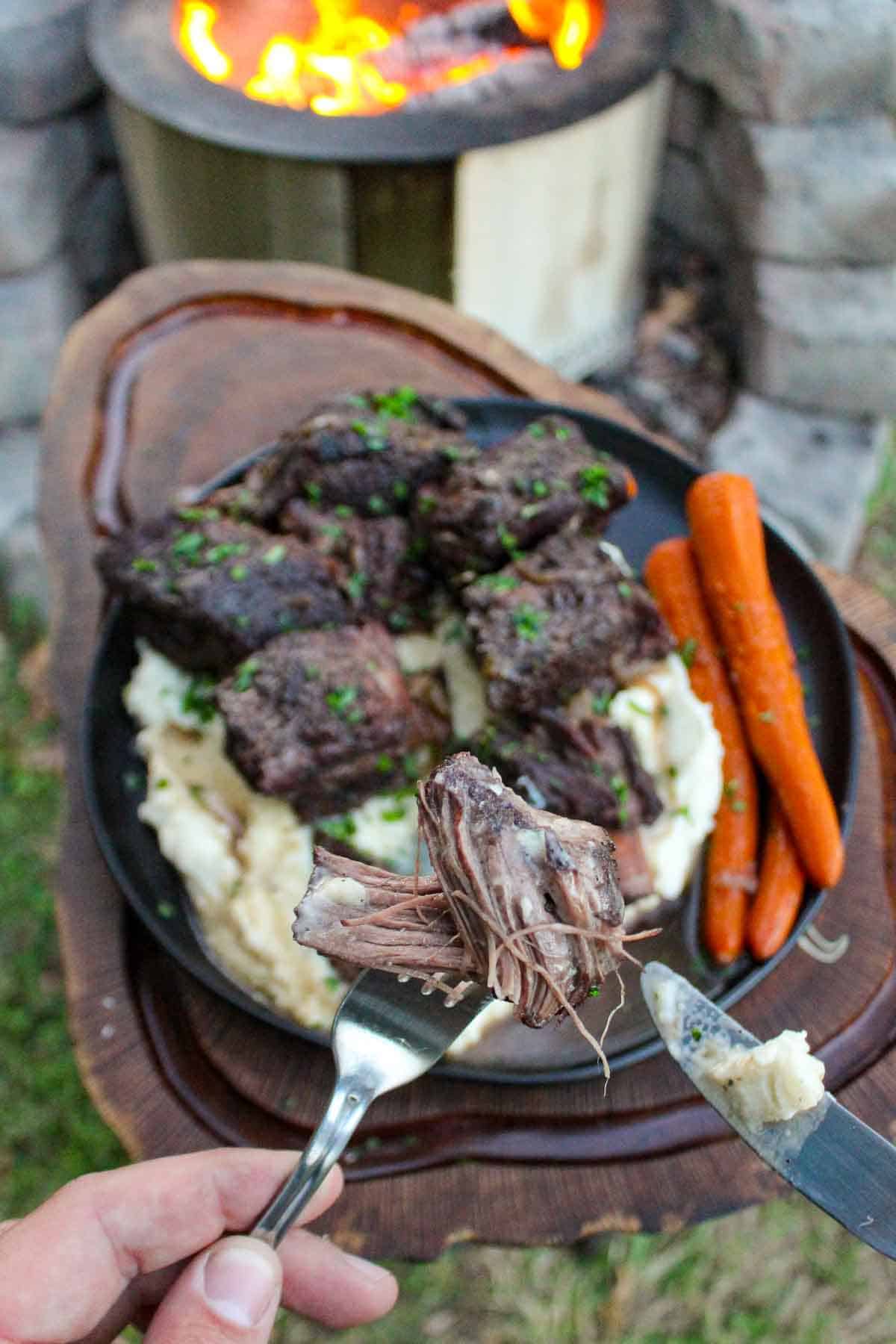 Tender beef from braised beef ribs being held up to the camera. 