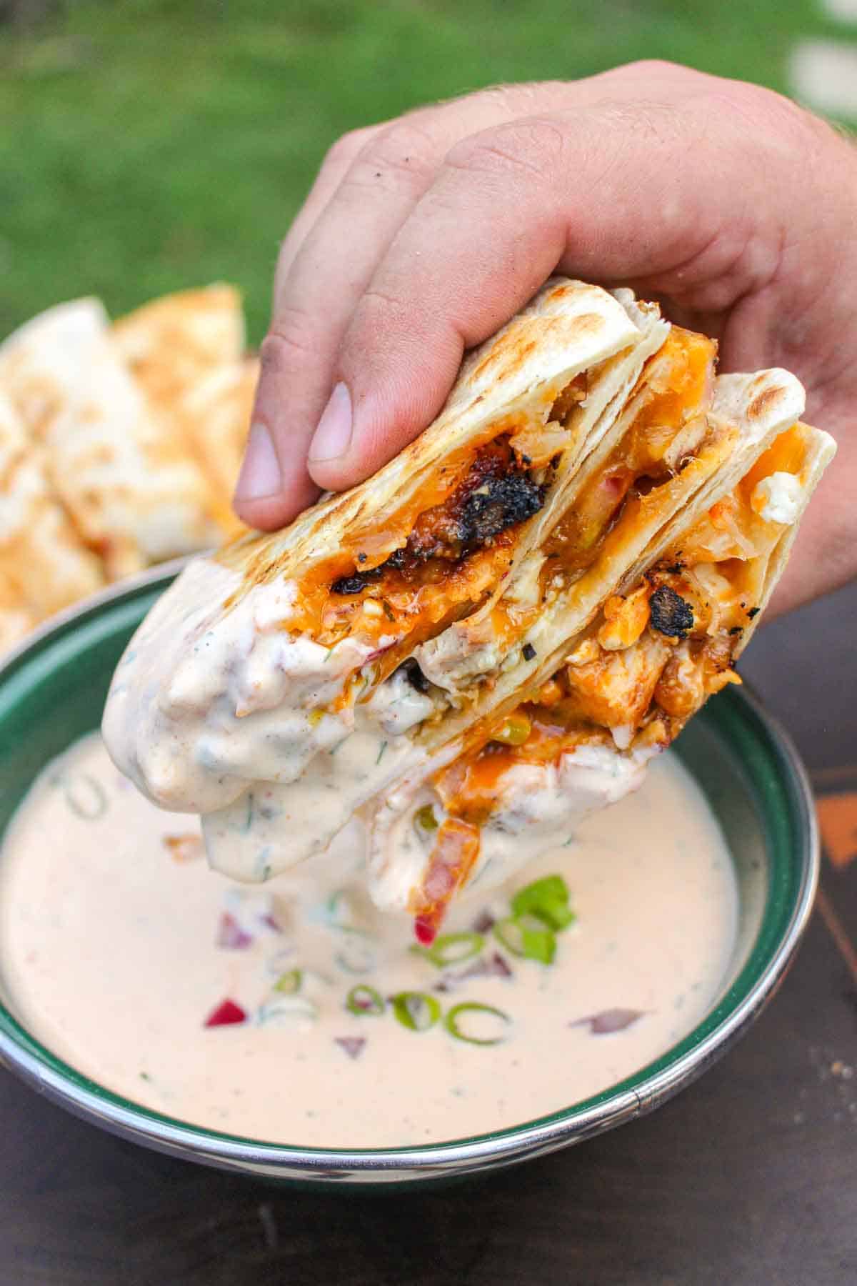 Buffalo chicken quesadilla recipe sliced open and dipped in sauce