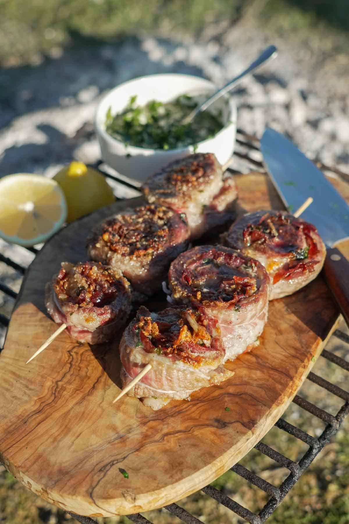 A plate of pork pinwheels with wooden skewers and mojo verde sauce on the side