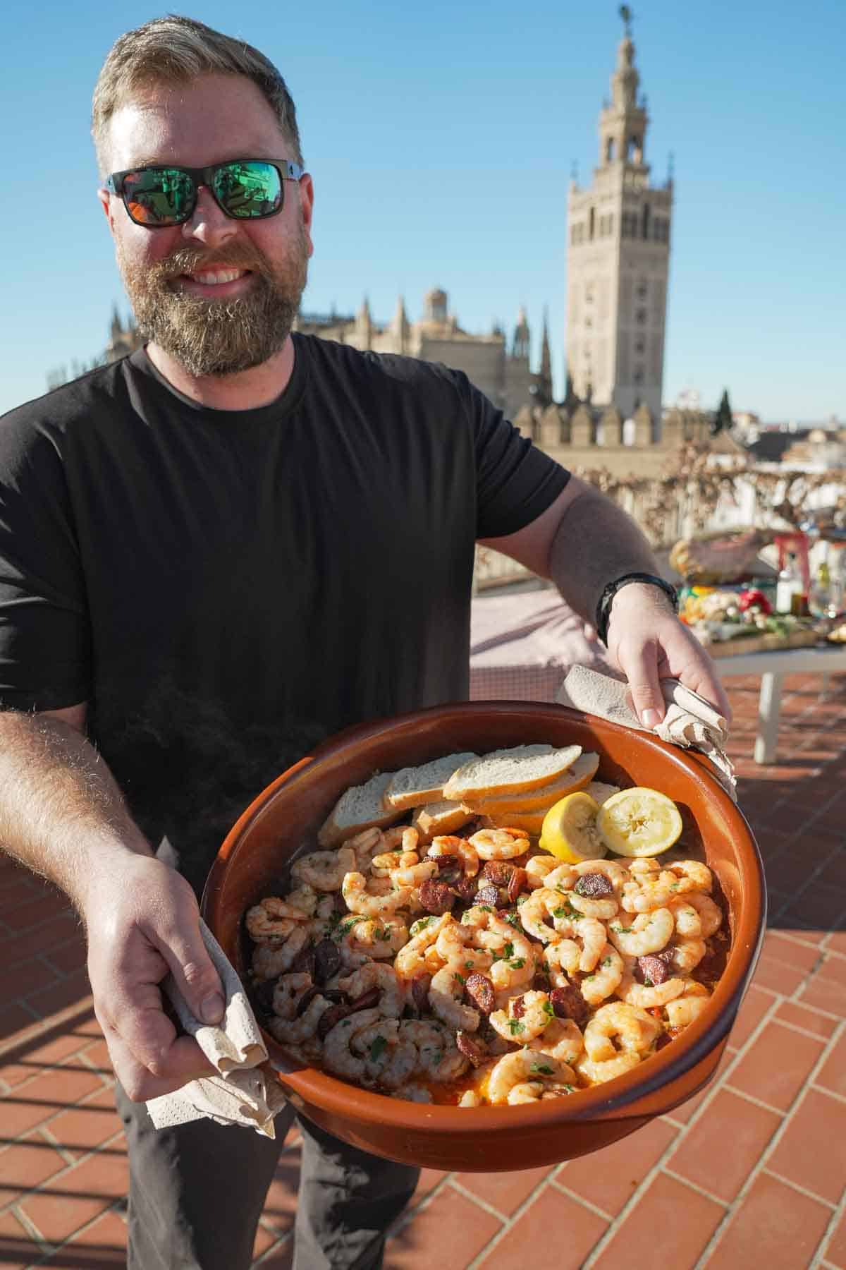 Derek holds up the bowl of Garlic Chorizo Shrimp, smiling because he knows how good it's going to taste.