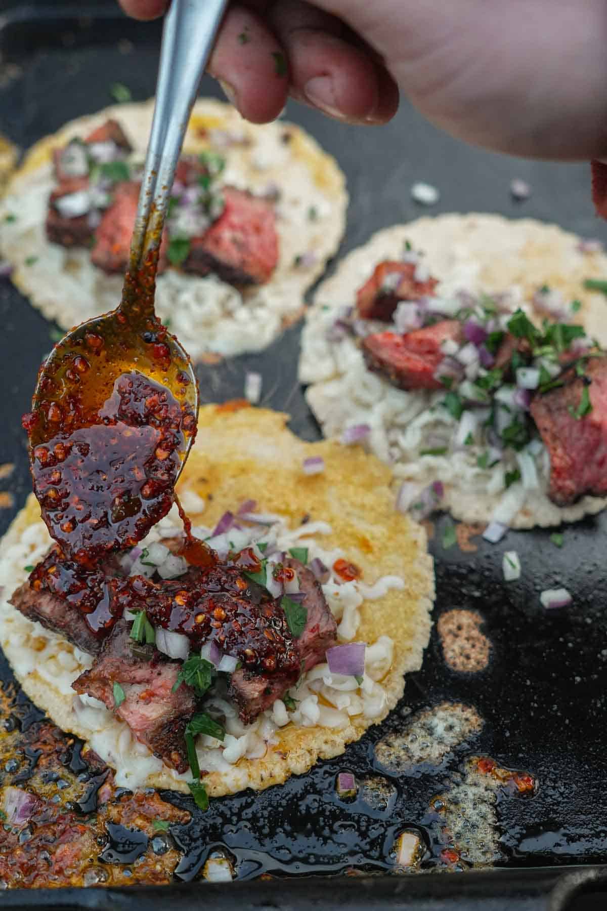 The fiery red chili sauce is drizzled over the inside of the tacos.