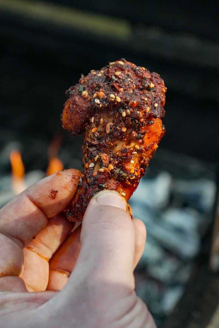 A hand holding a single hot honey wing with chili crisp