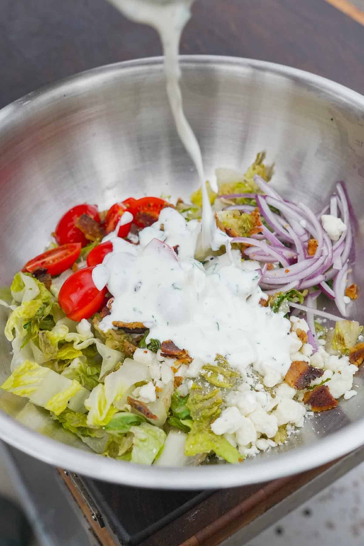 Adding homemade ranch dressing to a garden salad