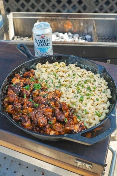 A cast iron skillet filled with BBQ chicken and beer cheese macaroni and a can of Samuel Adams in the background