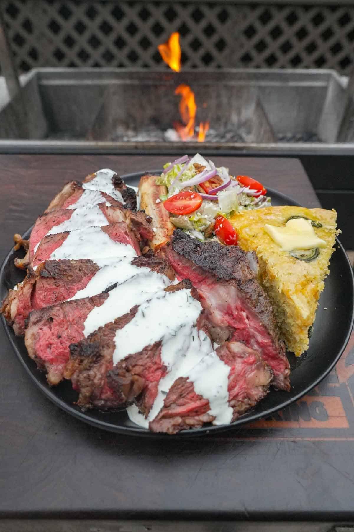 Final shot of the completed recipe with steak, cornbread, and salad. 