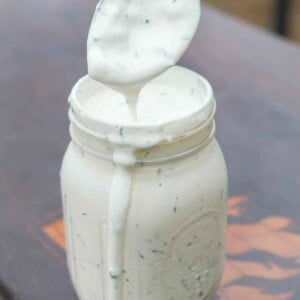 A mason jar filled with homemade ranch dressing and a spoon covered in dressing