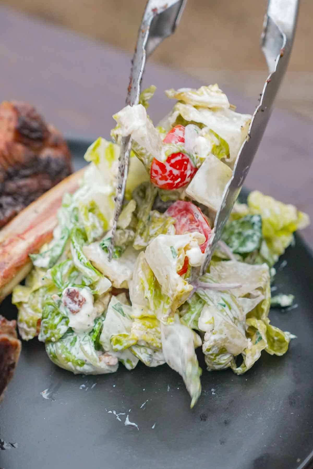 Tossing a garden salad using tongs on a plate