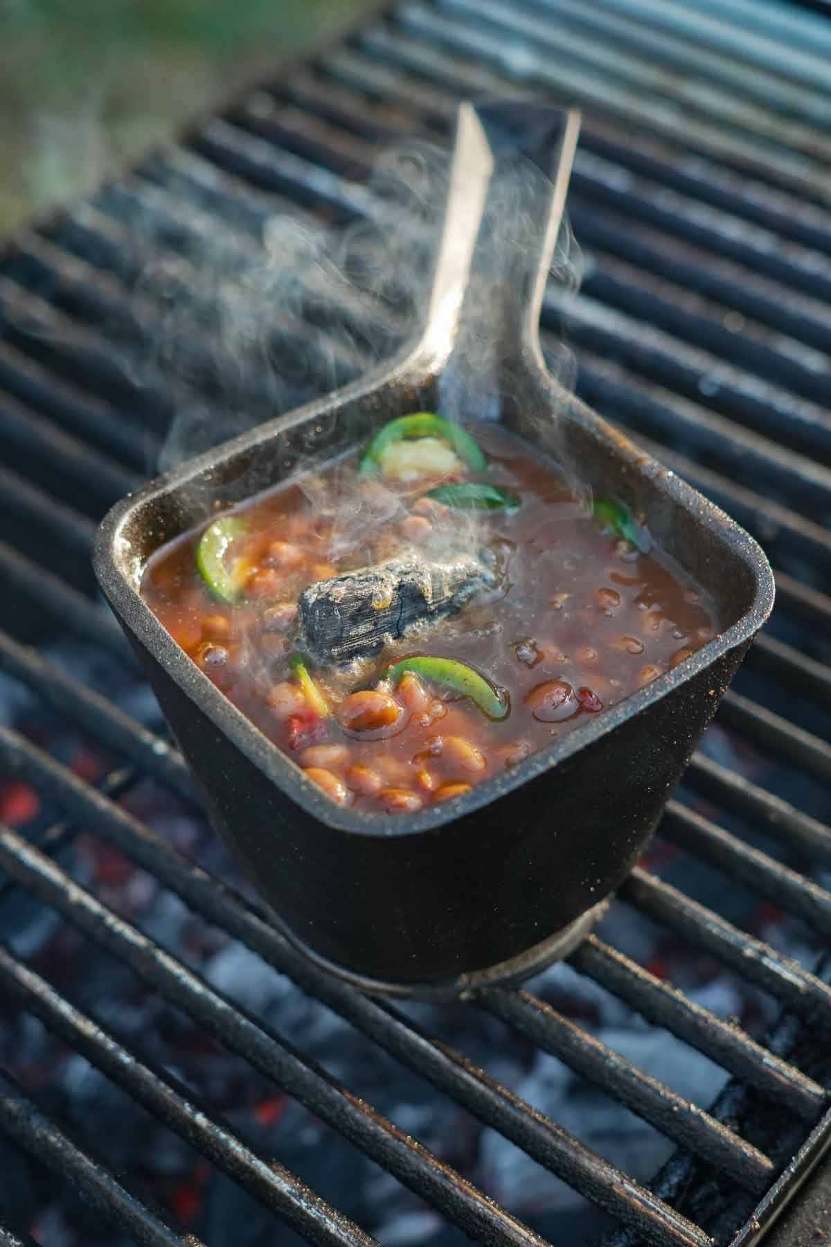 Saucy Spoon roasted chipotle beans in a small cast iron skillet on the grill