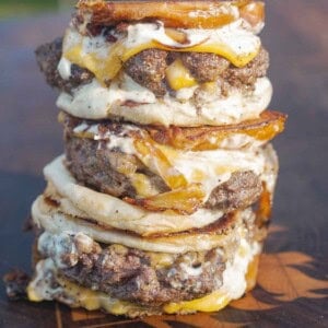 A stack of stuffed patty melts with burger buns, meat patties, bacon and garlic aioli