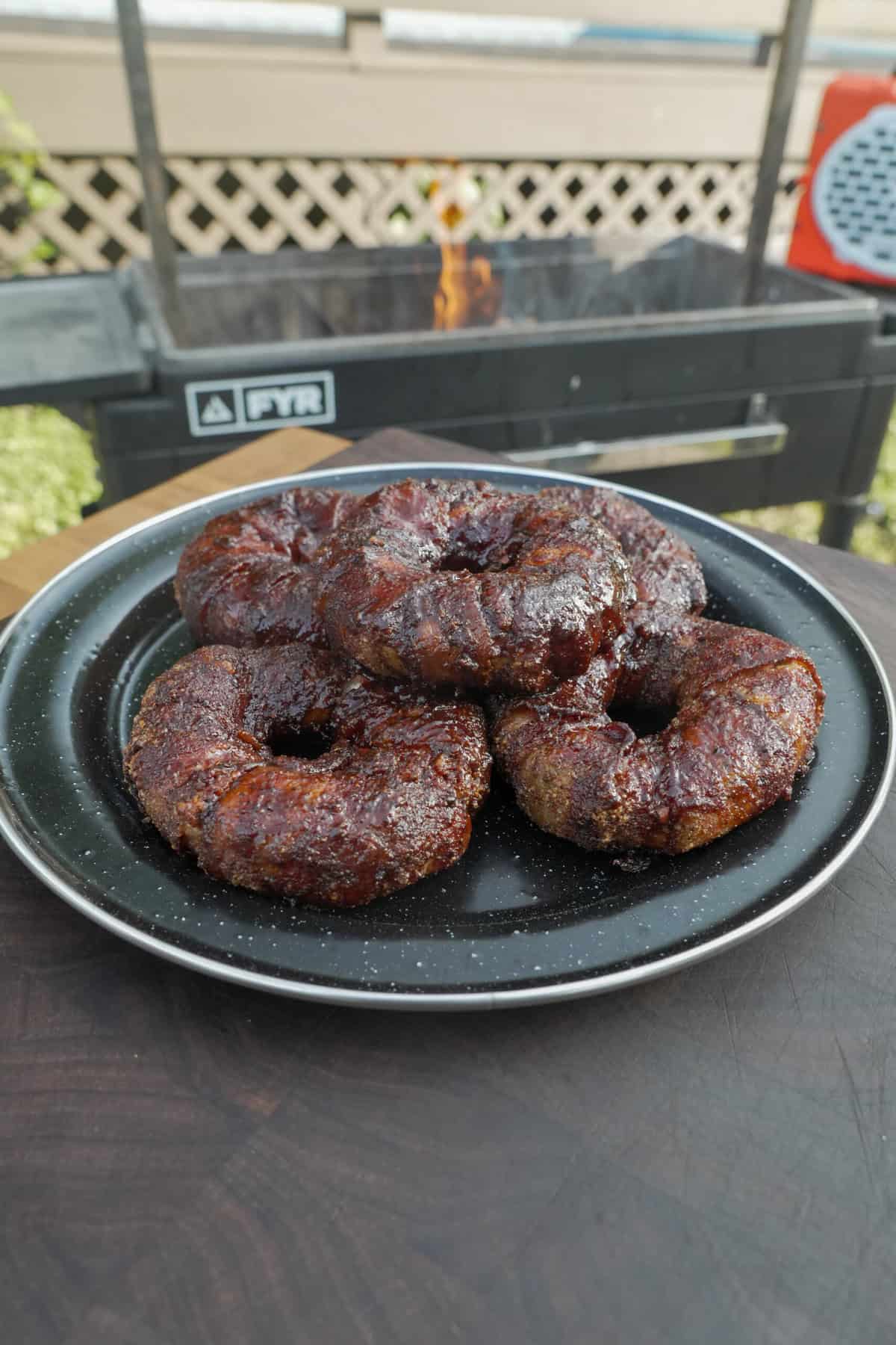 A plate of finished Texas Twinkie stuffed onion rings in front of the grill