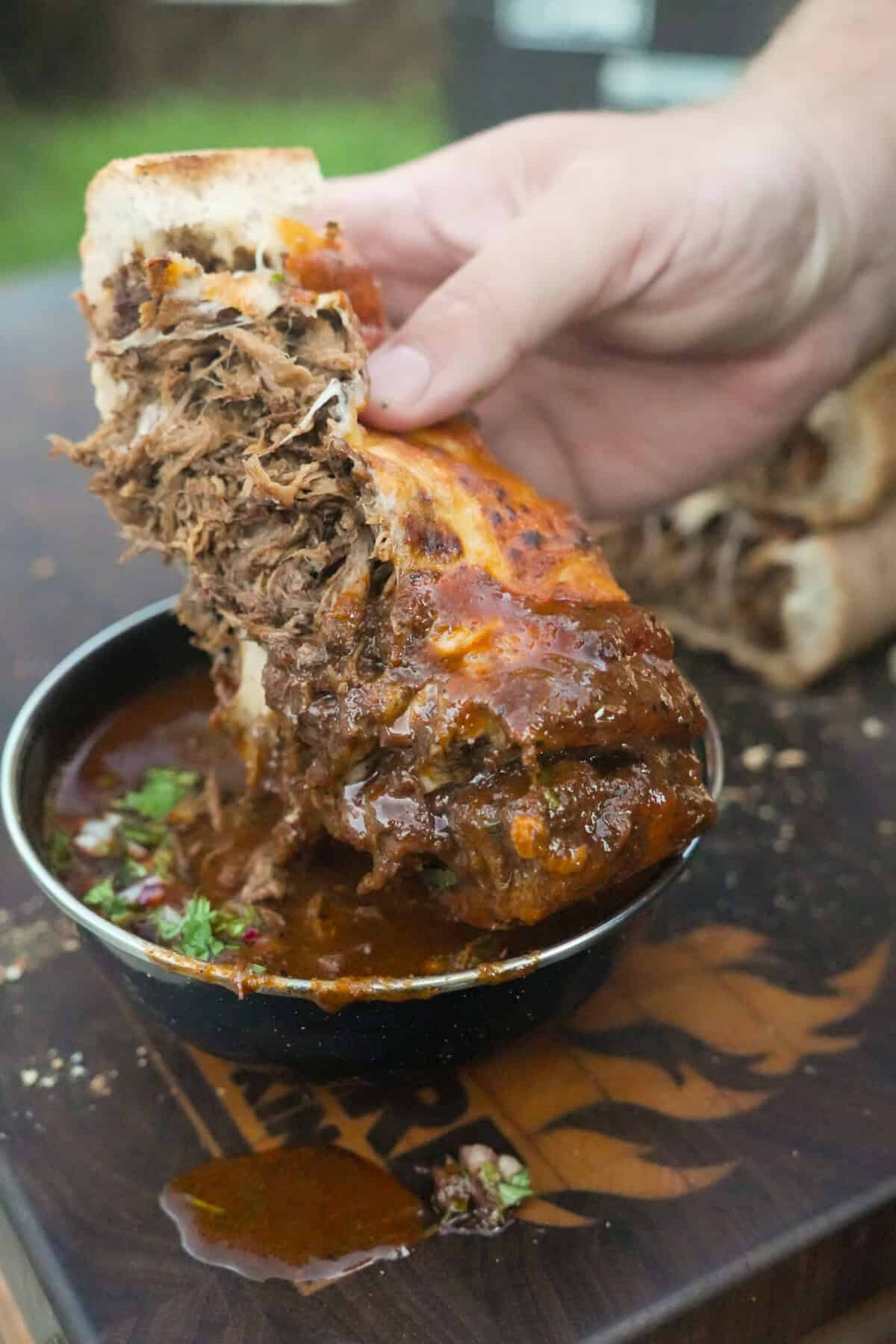 The stuffed bread is dipped into the beef birria sauce for a bite you won't believe.