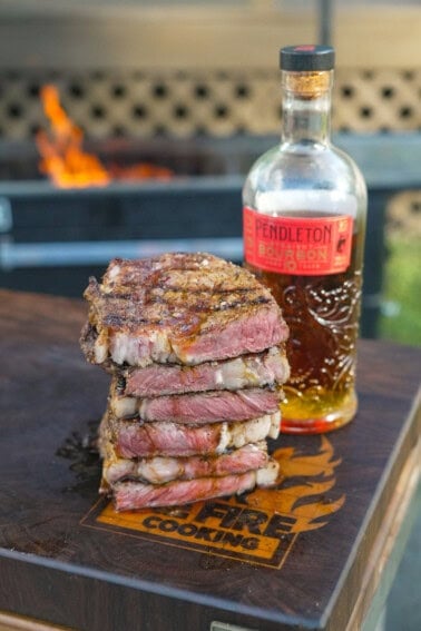 A stack of sliced grilled steaks with bourbon butter and a bottle of Pendleton Whisky