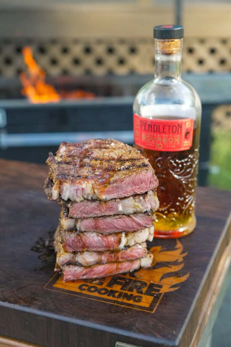 A stack of sliced grilled steaks with bourbon butter and a bottle of Pendleton Whisky