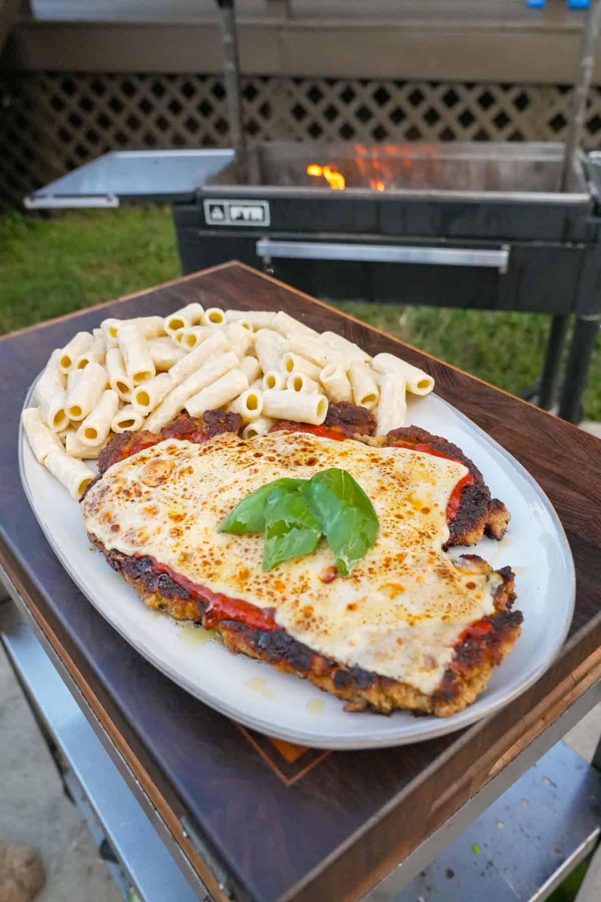 The finished meal with breadcrumb coating and marinara sauce, mozzarella and fresh basil on top, with alfredo rigatoni on the side