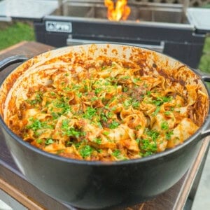 A finished pot of braised beef ragu, tossed with pasta and garnished with chopped parsley and Parmesan cheese