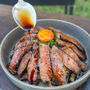 The umami sauce is drizzled over our ribeye steak slices laying artfully over a bed of rice with an egg yolk in the center.