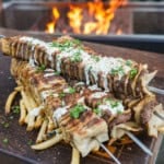 Tortilla Kebabs are done, drizzled with the creamy jalapeno sauce and layered over a bed of crispy French fries.